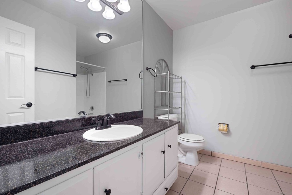 Gilroy, CA Apartments - Mission Park - Bathroom With Tiled Flooring, Toilet, Large Vanity Mirror, Wide Countertop, And A Shower