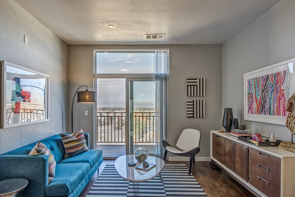 a living room with a blue couch and a sliding glass door to a balcony