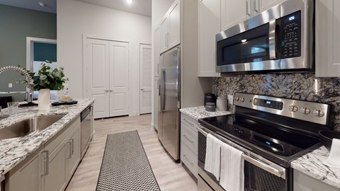 A modern kitchen with a stainless steel refrigerator and oven.