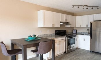 large kitchen with white cabinets and stainless steel appliances set against stone counter tops and modern furnishings - Photo Gallery 5