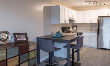 large kitchen with white cabinets and stainless steel appliances set against stone counter tops and modern furnishings - Photo Gallery 6