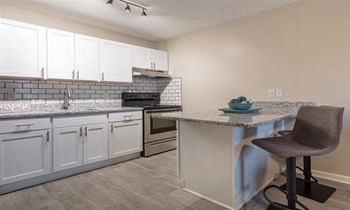 large kitchen with white cabinets and stainless steel appliances set against stone counter tops and white subway tile backsplash - Photo Gallery 3
