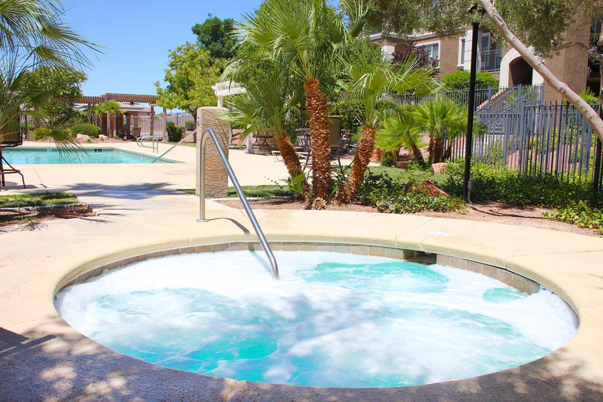 Apartments in Henderson NV-Avalon at Seven Hills Swimming Pool Surrounded By Lush Landscaping, Lounge Chairs, and a Spa