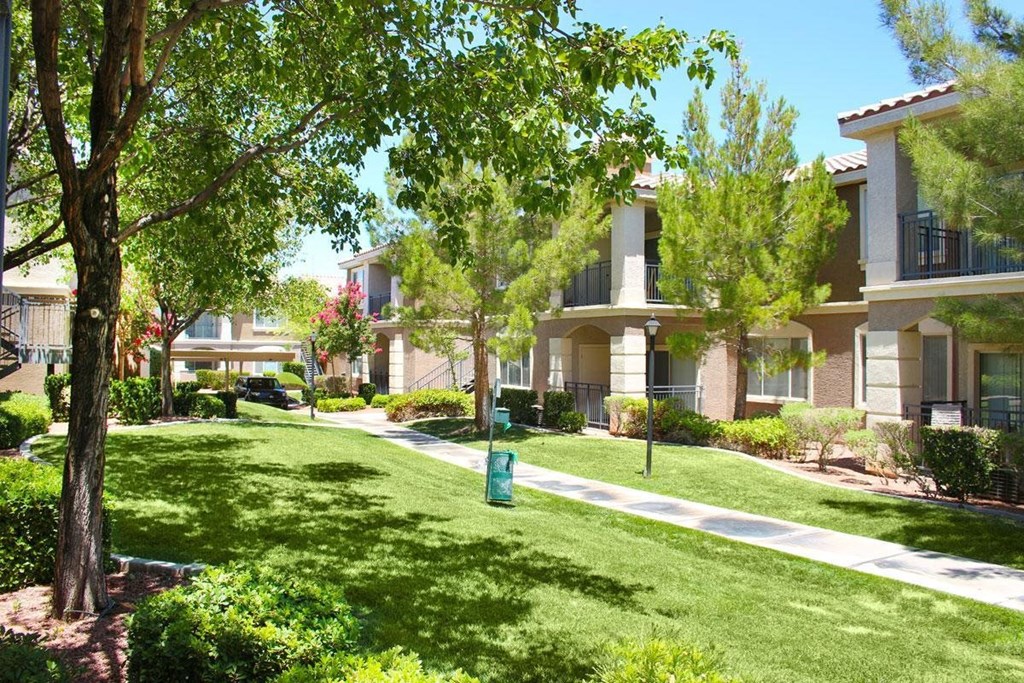 an apartment building with a green lawn and trees
