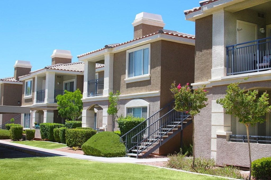 an apartment building with stairs and balconies on a sunny day