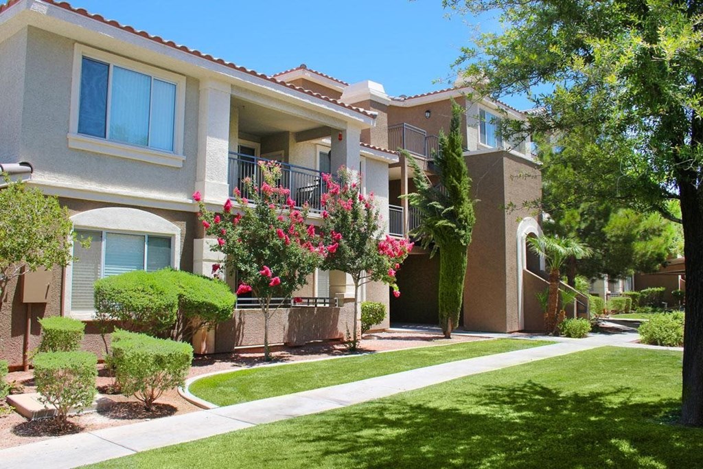 an apartment building with a sidewalk and lawn in front of it
