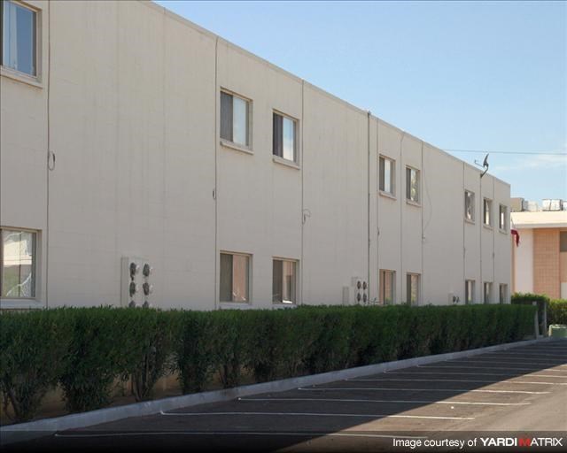 a white building with a row of hedges in front of it
