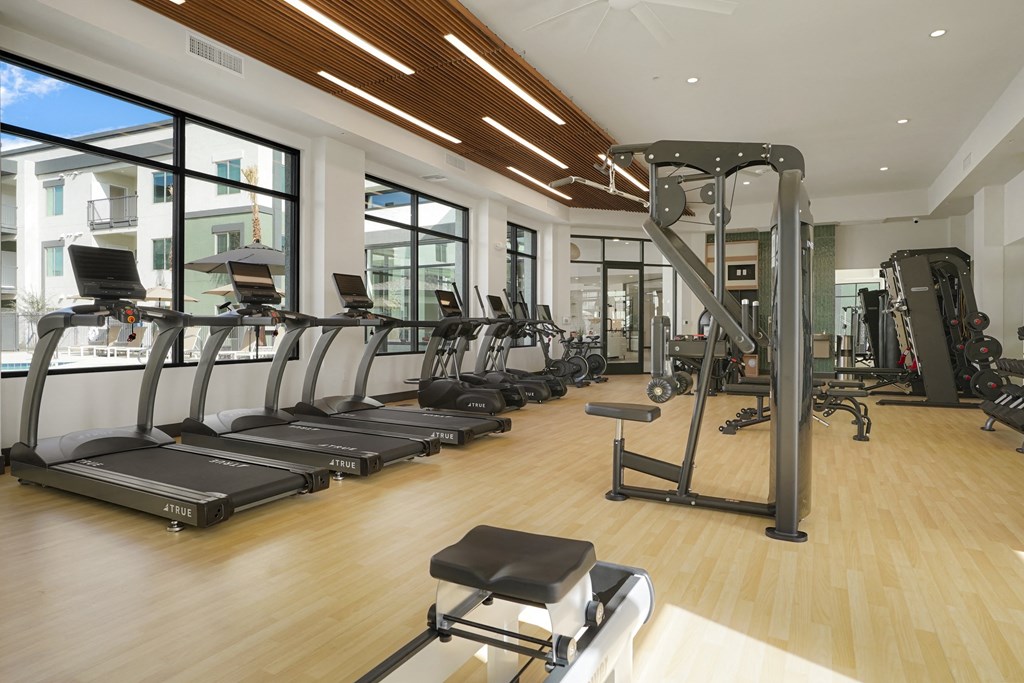 a gym with cardio equipment and windows in a building
