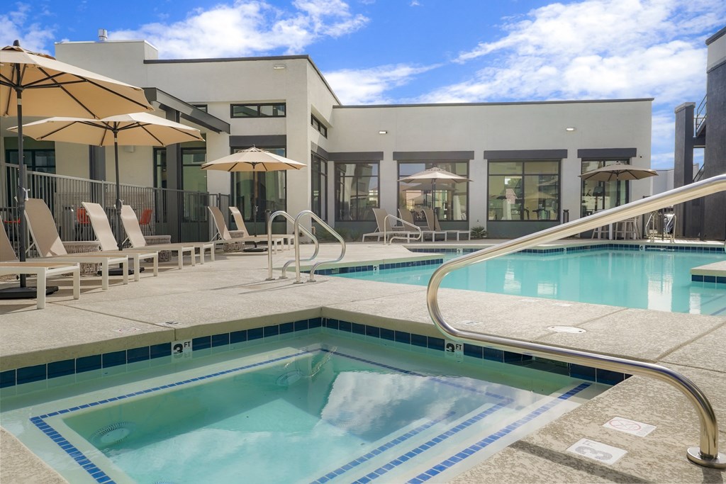 a swimming pool with chairs and umbrellas in front of a building