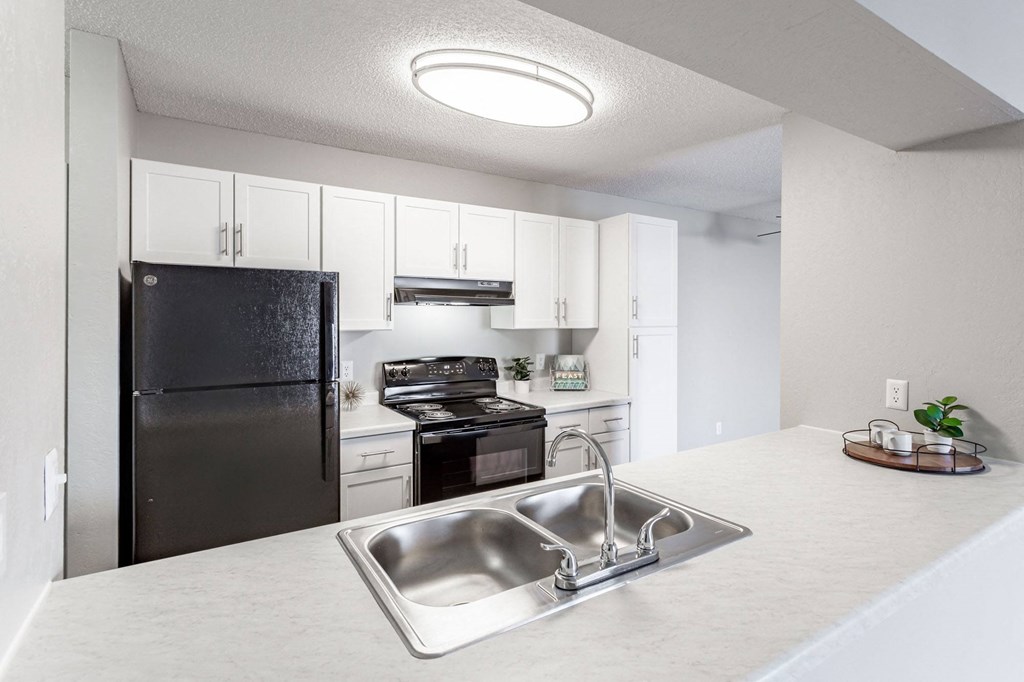 a kitchen with white cabinets and black appliances