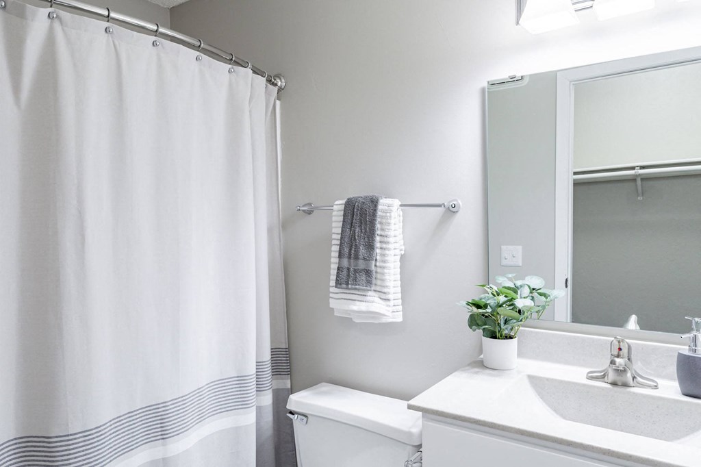 a bathroom with a white sink and toilet and a white shower curtain