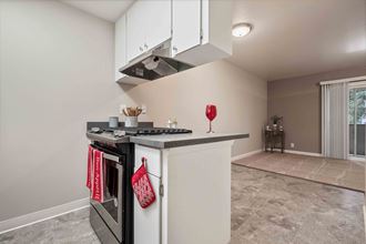 Apartments in Fremont, CA- Northgate Savoy- Kitchen Area with Stove, Oven, and Hanging Cabinets Adjacent to Living Room - Photo Gallery