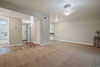 a spacious living room with a kitchen in the background - Photo Gallery