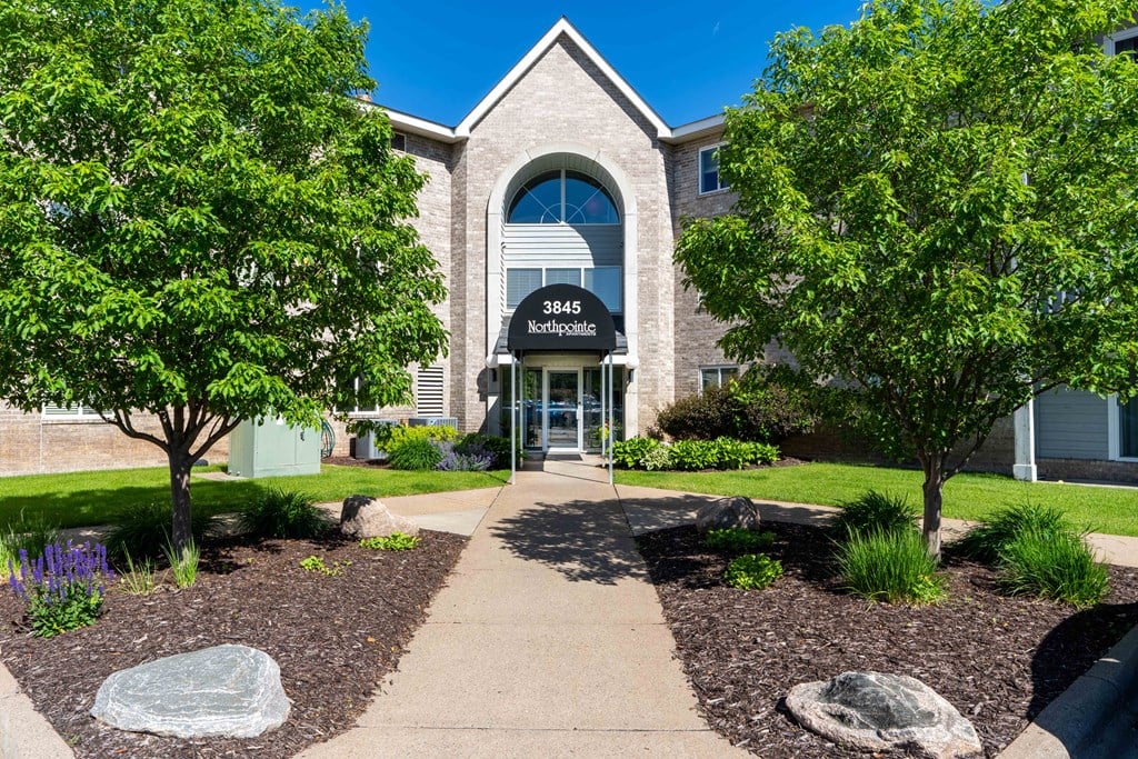 the front of a building with a sidewalk and trees