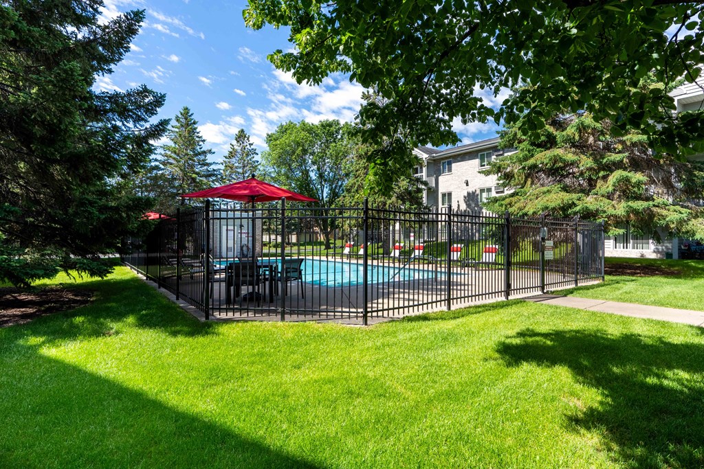 a fenced in pool with a table and umbrella in a yard