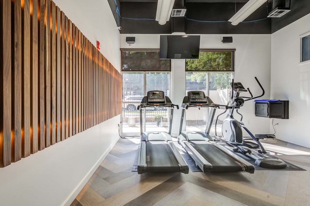 two treadmills in a gym with a window and a wall of wood panels