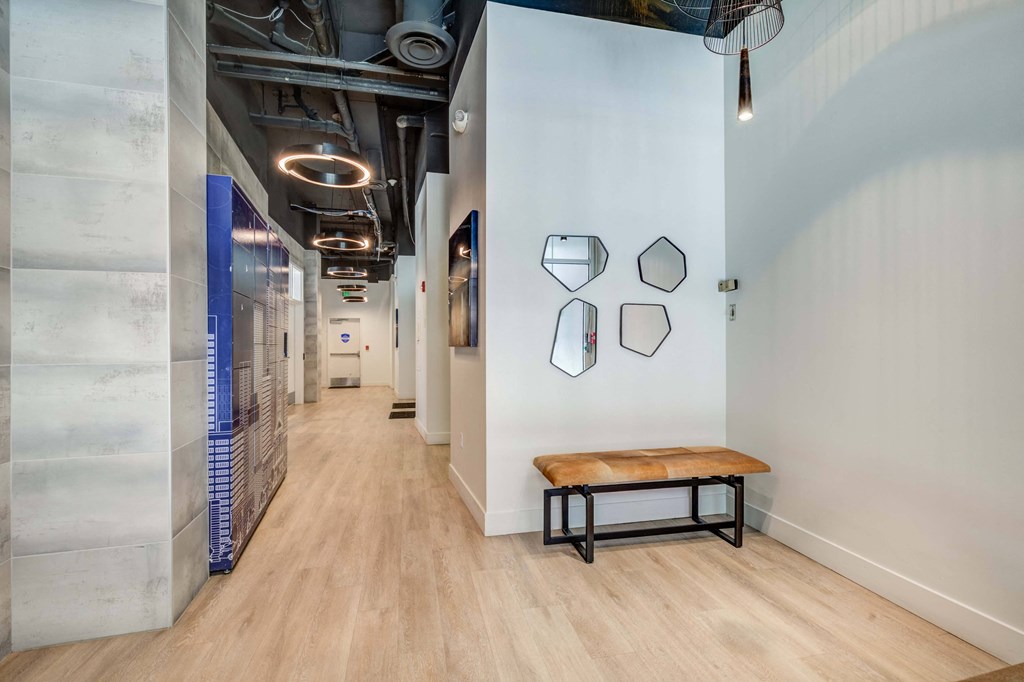 a hallway with a bench and a white wall with mirrors on it