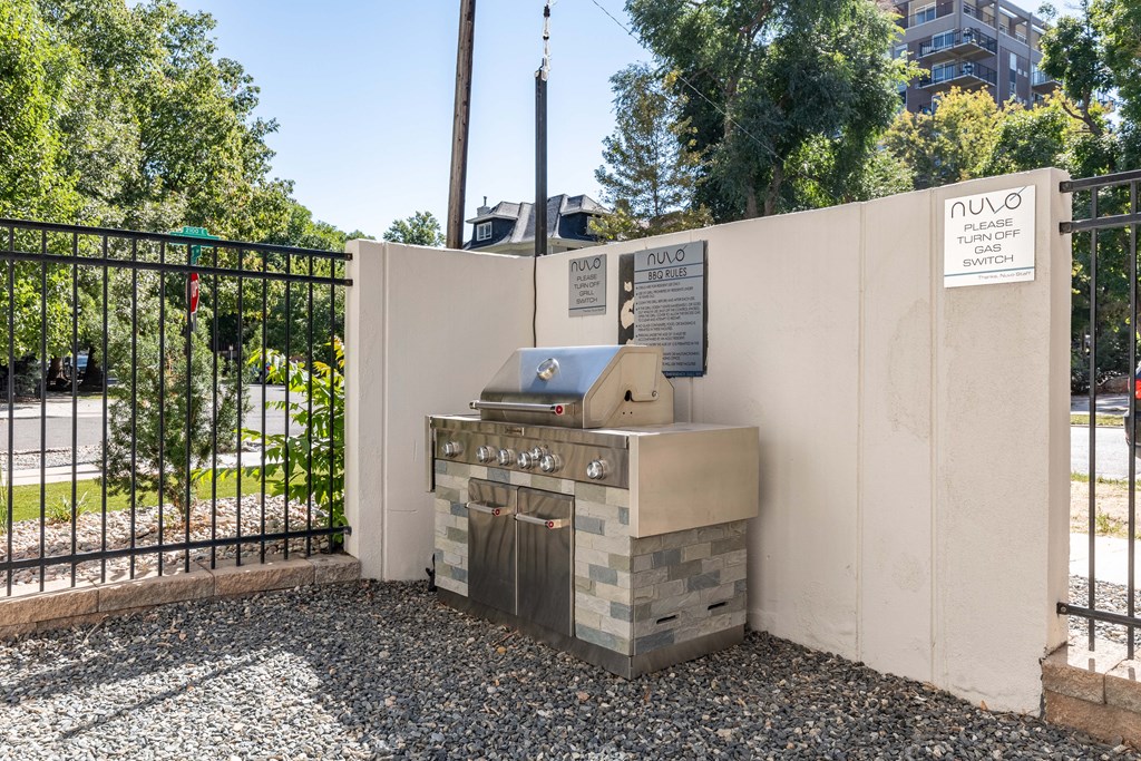 a barbecue grill in the corner of a wall next to a fence