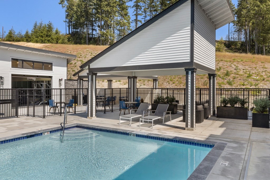 a swimming pool with chaise lounge chairs and a pool house with a gazebo,