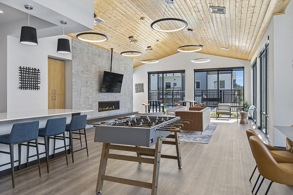 a communal area with a foosball table and chairs and a fireplace,