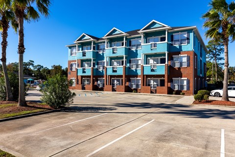 A multi-story building with a parking lot in front.