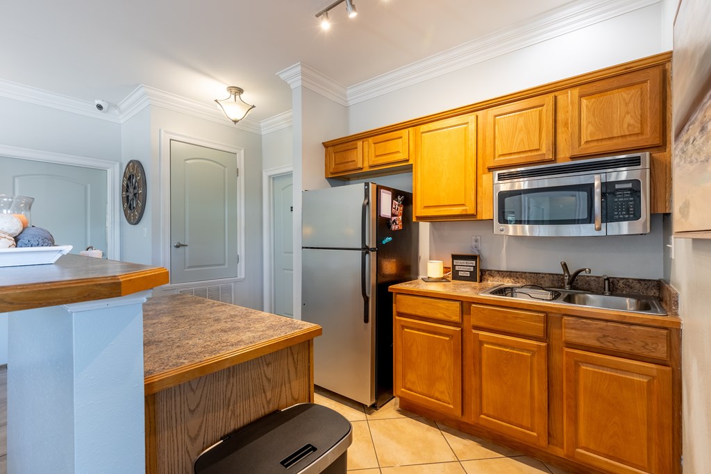 A kitchen with wooden cabinets and a black fridge.