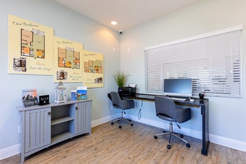 A room with a desk, chairs, and pictures of house floor plans.