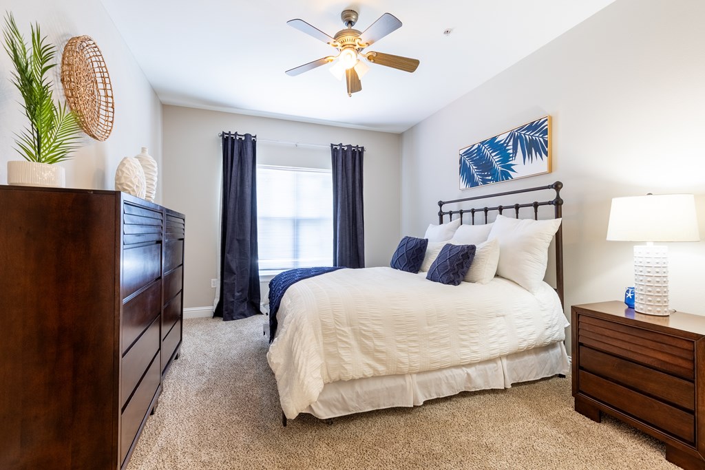 A bedroom with a bed, nightstand, and a ceiling fan.
