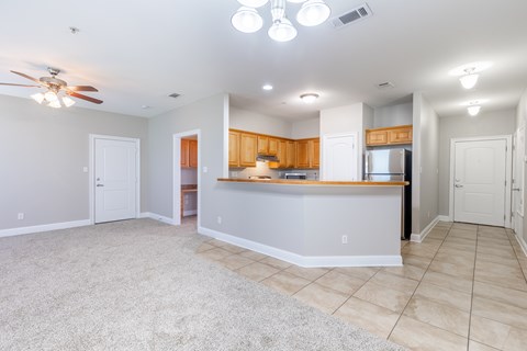 A spacious living room with a kitchen area in the background.