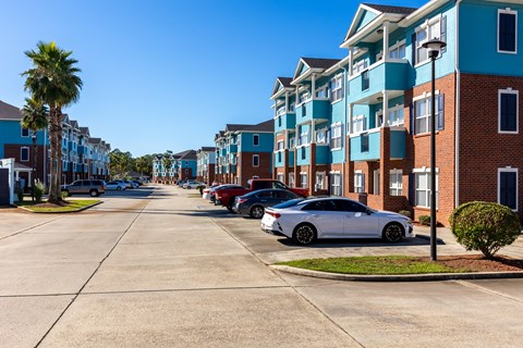A street view of a residential area with cars parked on the side.