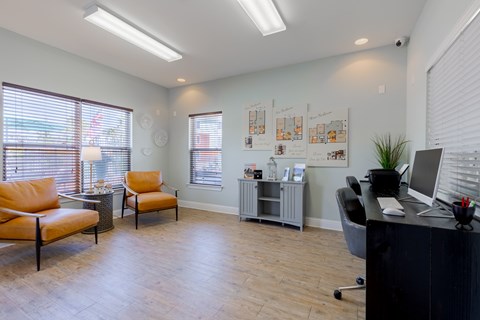 A room with a black desk and orange chairs.