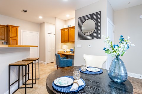 A dining table set with blue plates and a vase of flowers.