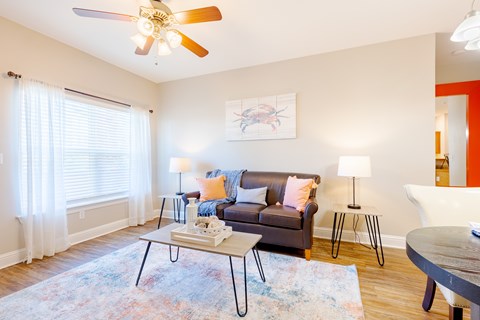 A living room with a couch, a coffee table, and a ceiling fan.