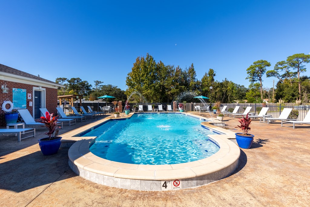 A swimming pool surrounded by lounge chairs and trees.