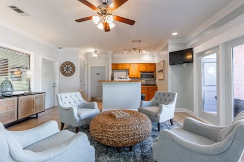 A living room with a white couch, a wicker coffee table, and a ceiling fan.
