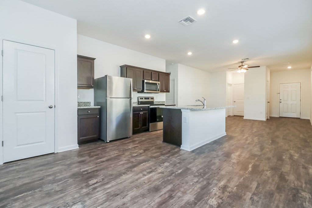 A kitchen with a refrigerator, microwave, and oven.