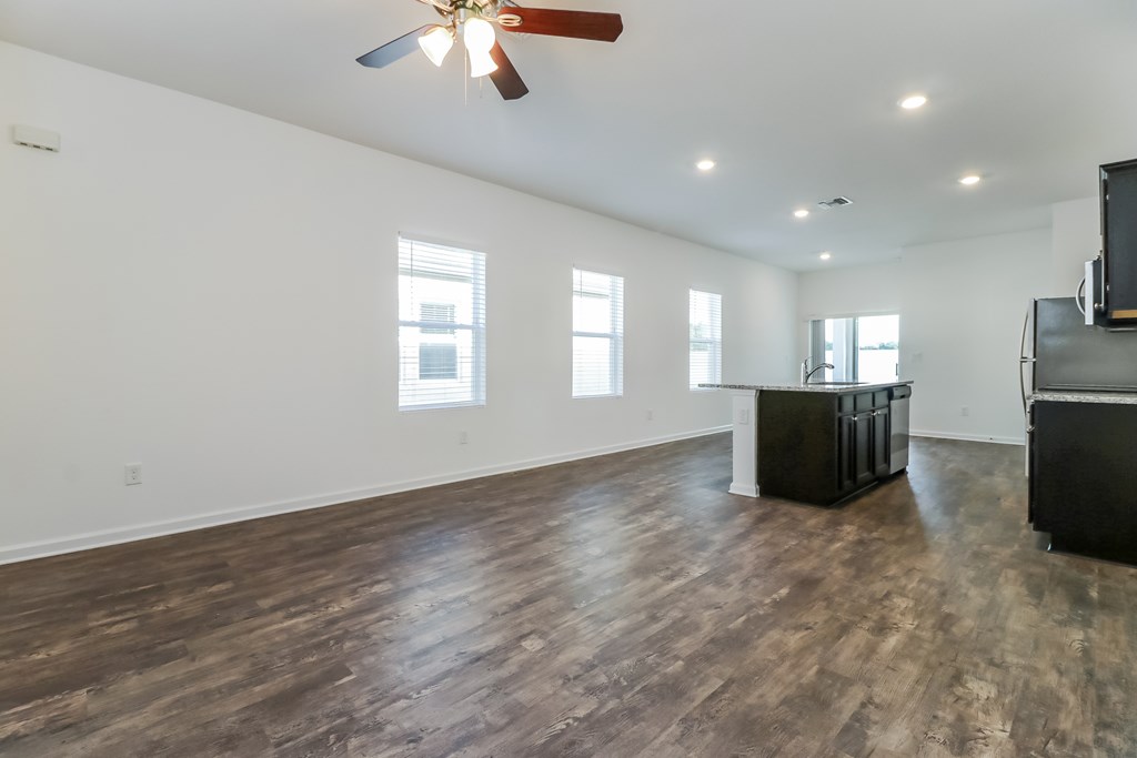 A room with a ceiling fan and wooden flooring.