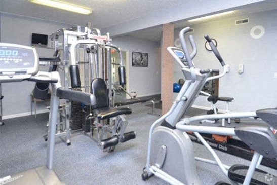 a gym with cardio equipment and weights on the floor