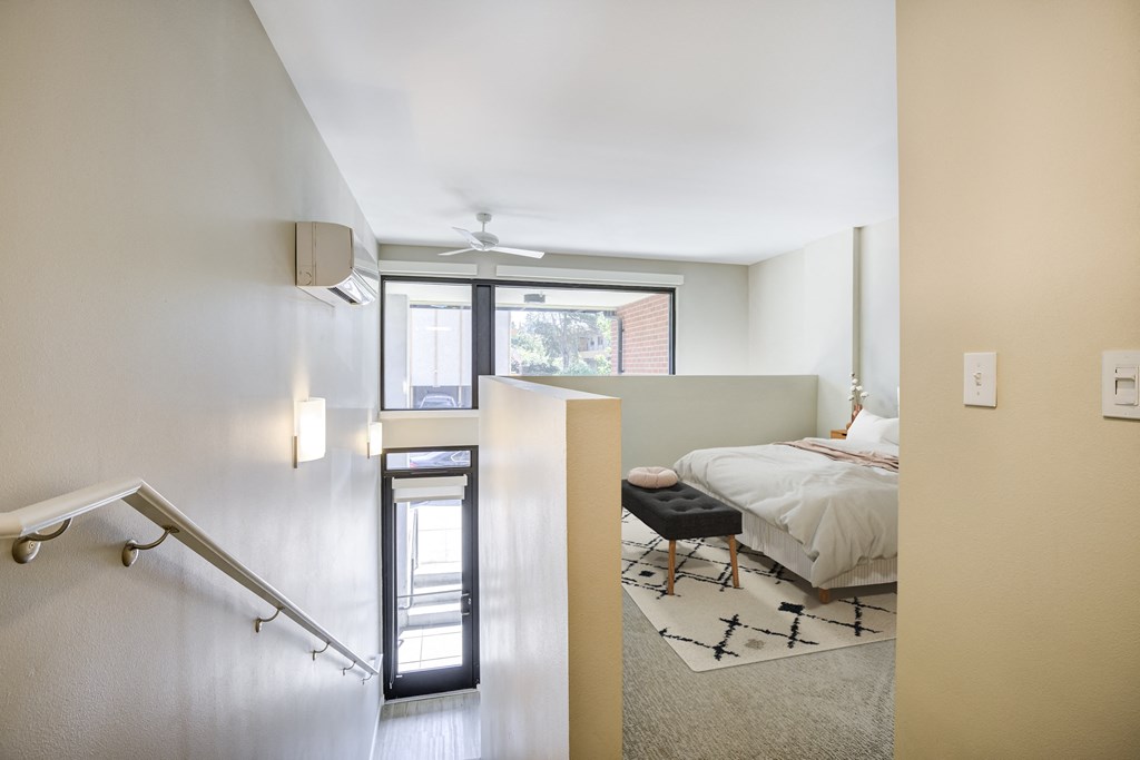 a bedroom with a bed and a stairway leading into a room