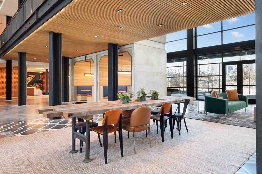 A modern dining area with a long table and chairs inside the Laura community lounge.