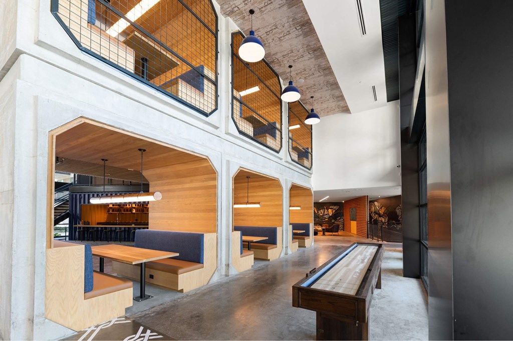 The Laura community lounge with wooden tables, benches, and a shuffleboard table..