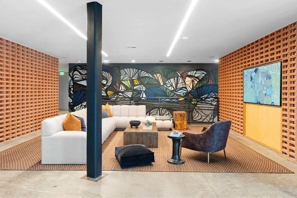 A modern seating with a large mural on the wall, couches, and a tv inside The Laura community lounge.