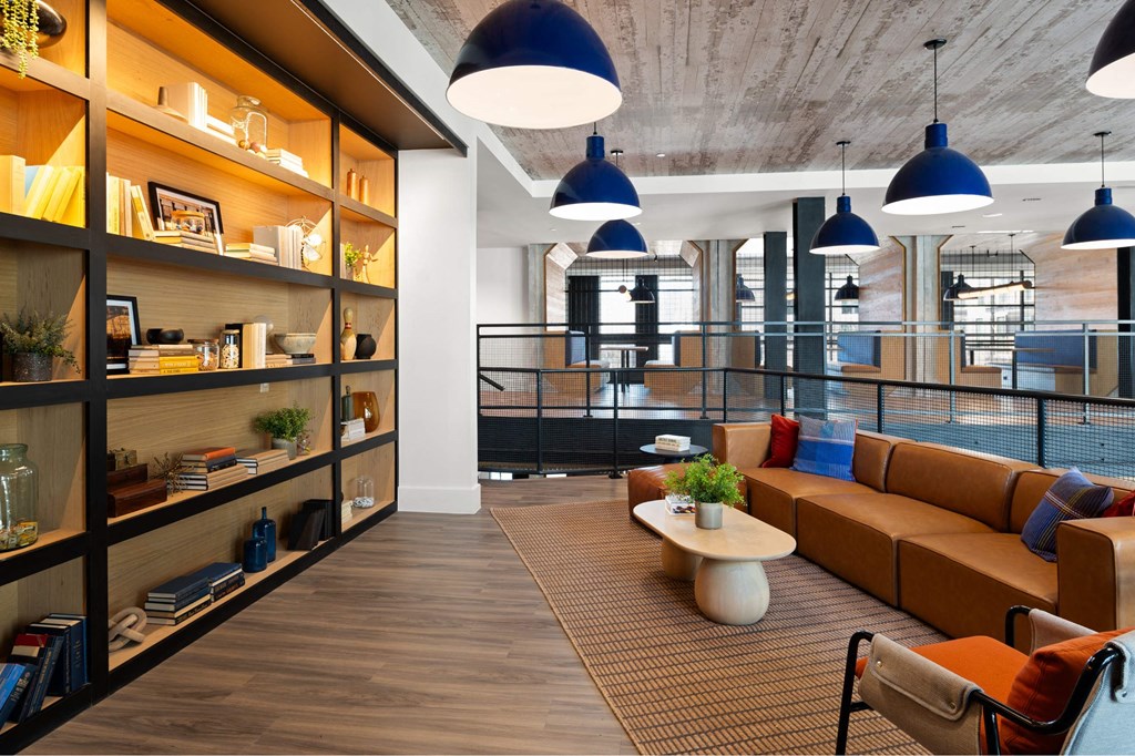 A modern seating area inside The Laura office with a long wooden shelf on the left side and a brown sofa in the center.
