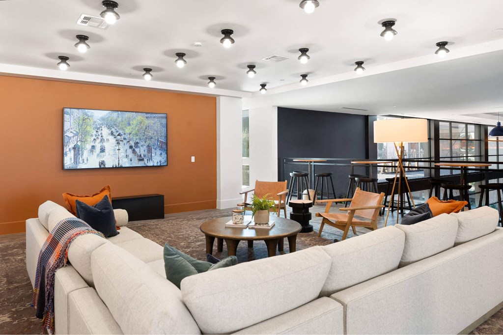 A resident lounge with a large couch, a coffee table, and a painting on the wall.