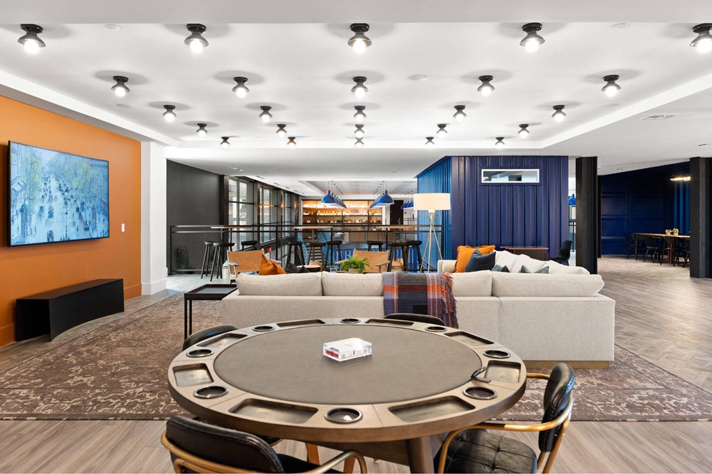 A modern resident lounge with a round poker table and chairs.