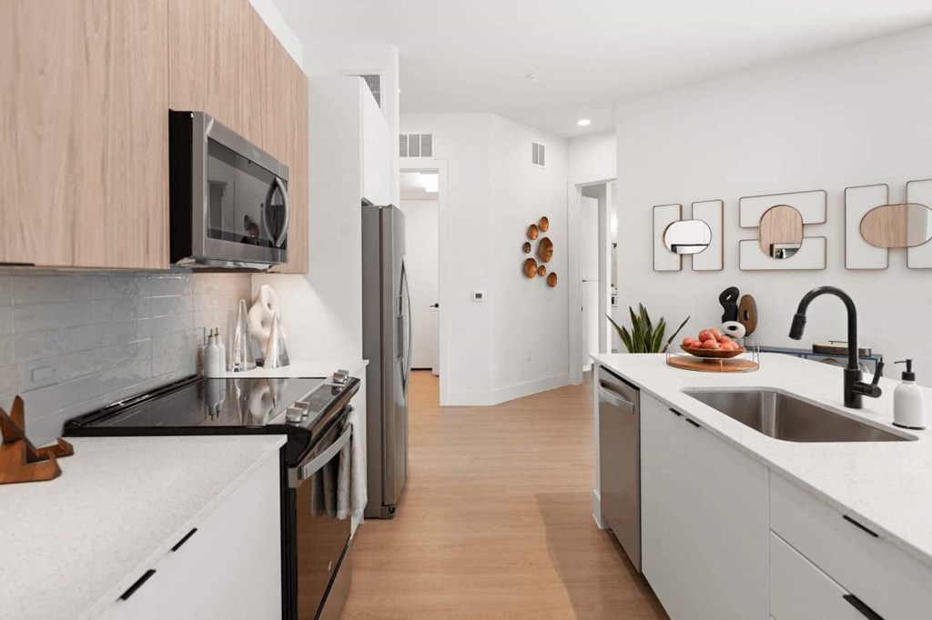 A modern kitchen with white countertops and wooden cabinets at The Laura apartment complex in Houston, TX