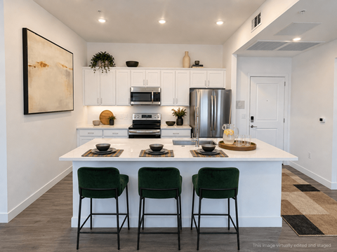 A kitchen with white cabinets and a white island with green chairs.