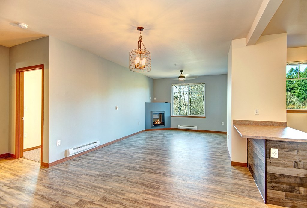 an empty living room with a fireplace and a wooden floor
