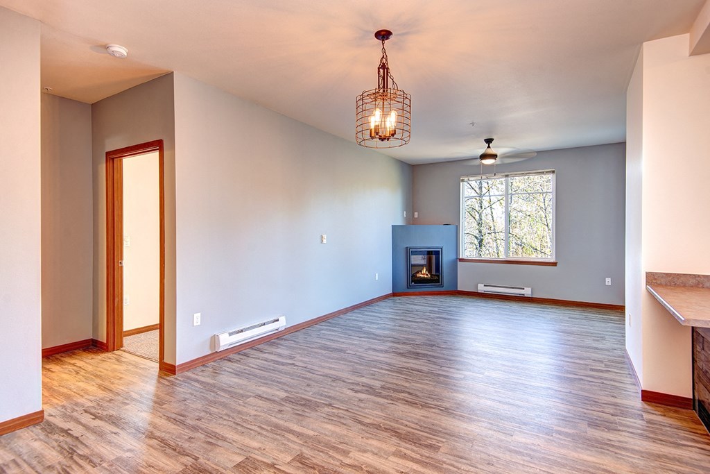 an empty living room with wood floors and a fireplace