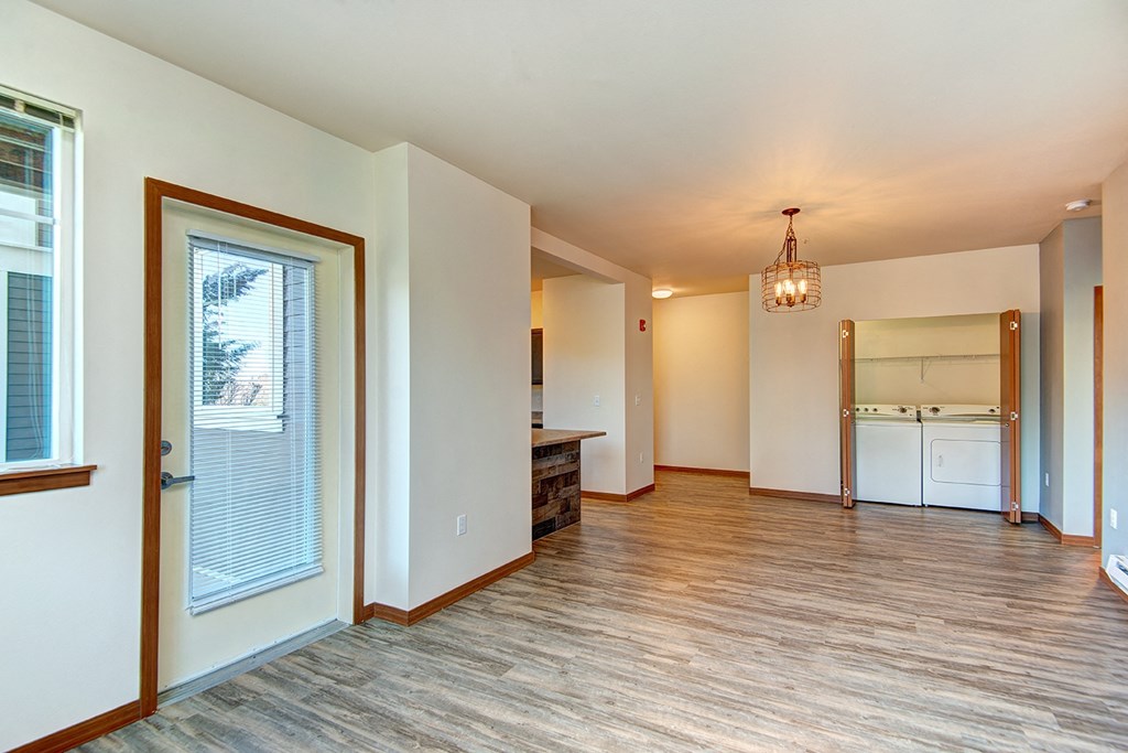 an empty living room with a door to a kitchen
